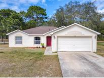 One-story house with attached garage, red door and well-manicured lawn at 3054 Shallowford St, Deltona, FL 32738