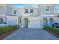 Two-story townhome with gray siding, paver driveway, and landscaping at 4708 Tribute Trl, Kissimmee, FL 34746