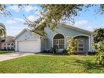 Charming light blue house with a white garage door and well-manicured lawn at 1004 Hornbeam St, Oviedo, FL 32765