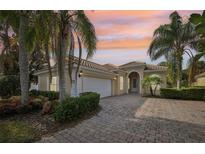 Charming single-story home with a brick driveway, lush landscaping, and a tile roof at sunset at 12161 Obelia Ln, Orlando, FL 32827