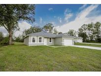 Newly constructed home with a green lawn and attached garage at 16391 Sw 17Th Terrace Rd, Ocala, FL 34473