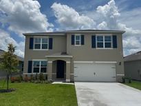 Two-story home with a front lawn and an attached two-car garage on a lot with a cloudy blue sky background at 2212 Lake Preserve Cir, New Smyrna Beach, FL 32168