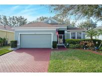 One-story house with a green exterior, red brick driveway and well-manicured lawn at 2311 Caledonian St, Clermont, FL 34711