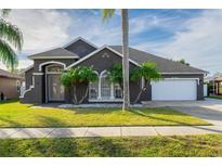 Gray house with palm trees, two-car garage, and well-manicured lawn at 2566 Ballard Ave, Orlando, FL 32833