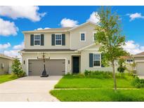 Two-story house with gray siding, dark shutters, and a basketball hoop in the front yard at 332 Bow Ln, Haines City, FL 33844