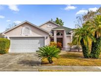 Pink house with white garage door and landscaping at 3890 Waterview Loop, Winter Park, FL 32792