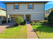 Charming two-story home with attached garage, neat landscaping, and a brick walkway leading to the front door at 1312 Shinnecock Hills Dr, Davenport, FL 33896