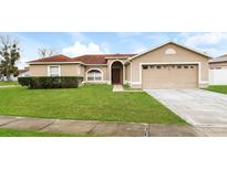 Tan one-story house with a two-car garage and well-maintained lawn at 2543 Sage Dr, Kissimmee, FL 34758