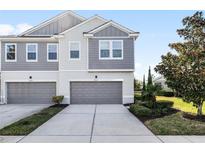 Two-story townhome with gray siding, two-car garage, and landscaping at 9053 Shepton St, Orlando, FL 32825