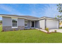 One-story home with gray exterior, stone accents, and a white garage door at 943 Derbyshire Dr, Kissimmee, FL 34758