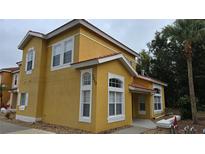 Two-story yellow house with white trim, and a landscaped yard at 1013 Park Ridge Cir, Kissimmee, FL 34746