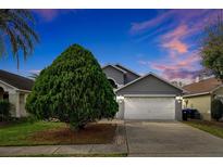 Gray house with white garage door, landscaping, and a driveway at 12821 Gettysburg Cir, Orlando, FL 32837