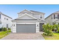 Two-story house with gray siding, a gray three-car garage, and a brick paver driveway at 2438 Pearl Cider Street, Orlando, FL 32824