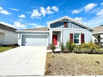 One-story home with gray siding, red door, and landscaped yard at 245 Lawson Ave, Haines City, FL 33844