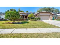 Brick house with solar panels, well-manicured lawn, and a two-car garage at 1107 Seafarer Ln, Winter Springs, FL 32708