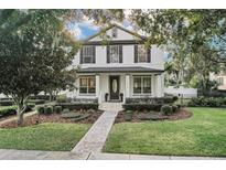 Charming two-story home with a well-manicured front yard, inviting curb appeal, and a cozy front porch with beautiful landscaping at 11413 Camden Park Dr, Windermere, FL 34786