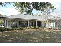 Expansive backyard featuring a covered patio, lush greenery, and mature trees providing ample shade at 1821 Stanley St, Longwood, FL 32750