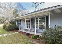 Charming single story home featuring a covered porch, white columns, and decorative front door wreaths at 1821 Stanley St, Longwood, FL 32750