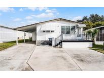 White single-wide manufactured home with carport and small deck at 50989 Highway 27 # 25, Davenport, FL 33897