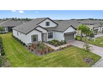 Two-story house with gray roof, landscaping, and brick driveway at 960 Ladera Ranch Rd, Poinciana, FL 34759