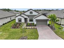 Beautiful two-story home with gray shingle roof, landscaping, and brick driveway at 960 Ladera Ranch Rd, Poinciana, FL 34759