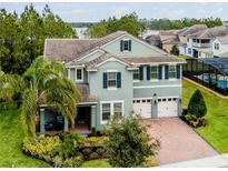 Two-story house with light teal exterior, paver driveway, and landscaping at 10219 Atwater Bay Dr, Winter Garden, FL 34787