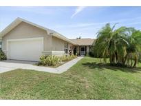 Tan house with white garage door and palm trees, a walkway to the entrance at 1423 Grand Cayman Cir, Winter Haven, FL 33884
