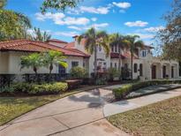 Stately two-story home boasts a clay tile roof, lush landscaping, and a long, curved driveway at 1446 Berkshire Ave, Winter Park, FL 32789
