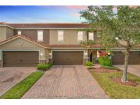 Tan three-story townhome with brown garage doors and landscaping at 2093 Leather Fern Dr, Ocoee, FL 34761