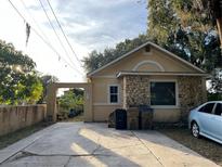 Charming single-story home featuring stone accents, a concrete driveway, and lush surrounding greenery at 2374 Ross St, Kissimmee, FL 34744