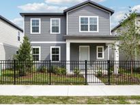 Charming two-story home with gray siding and a well-manicured front yard enclosed by a classic black metal fence at 2437 Zuni Rd, St Cloud, FL 34771