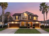 Two-story house with stone accents and a three-car garage; lovely landscaping at 3652 Chandler Estates Dr, Apopka, FL 32712