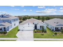 White house with gray roof, two-car garage, and landscaped yard at 7149 Dilly Lake Ave, Groveland, FL 34736