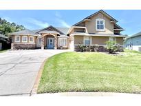 Inviting two-story home featuring manicured lawn, stone accents, and a circular driveway at 5210 Sailwind Cir, Orlando, FL 32810