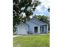 Cute light blue house with a white garage door and a nicely landscaped lawn at 89 Crooked Pine Rd, Port Orange, FL 32128