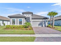 Charming single-story home with a tile roof, paver driveway, well-manicured lawn, and lush landscaping at 1511 Goblet Cove St, Kissimmee, FL 34746