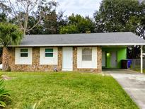 Charming single-story home featuring a stone facade, well-maintained lawn, and covered parking at 417 Benita St, Kissimmee, FL 34744