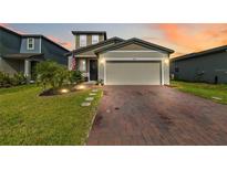 Charming two-story home featuring a brick driveway and attached two-car garage with a well manicured lawn at 494 Amadoras Way, St Cloud, FL 34771