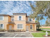 Two-story townhome with tan exterior, white trim, and landscaping at 2720 Bushman Dr, Kissimmee, FL 34746