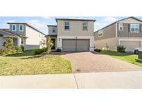 Two-story home with a two-car garage and well-manicured lawn in a modern neighborhood at 581 Sun Warbler Way, St Cloud, FL 34771