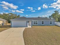 Newly built home with gray exterior, white garage door, and a paved driveway at 7080 Hemlock Crse, Ocala, FL 34472