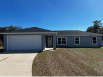 Newly constructed home with a gray exterior, two car garage, and a well-manicured lawn at 7080 Hemlock Crse, Ocala, FL 34472