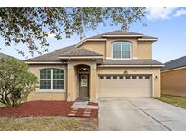 Charming two-story home featuring a manicured lawn, a two-car garage, and welcoming front entrance at 7525 Azalea Cove Cir, Orlando, FL 32807