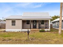 Charming single story home with gray siding, metal roof, and a welcoming front porch at 1114 Wyoming Ave, St Cloud, FL 34769