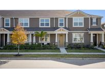 Two-story townhome with tan siding, a neutral-toned door and landscaping at 11574 Buoy Point Pl, Orlando, FL 32832