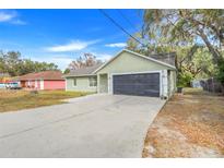 Light green house with black garage door and paved driveway at 1267 Varnado Rd, Groveland, FL 34736