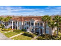 Two-story condo building with attractive landscaping and a tiled roof at 13917 Timberland Dr # 201, Orlando, FL 32824