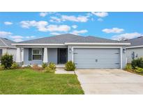 Single-story home with gray exterior, attached garage, and landscaped lawn at 220 Foxtail Loop, Davenport, FL 33837