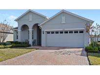 Gray house with a two-car garage and a brick paved driveway at 3999 Night Heron Dr, Sanford, FL 32773