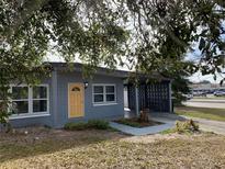 Newly painted gray house with yellow door, carport, and small front yard at 4400 Southmore Dr, Orlando, FL 32812